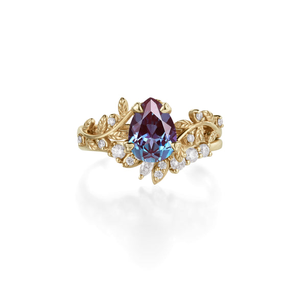 Elegant gold ring with pear-cut alexandrite center and botanical leaf accents.