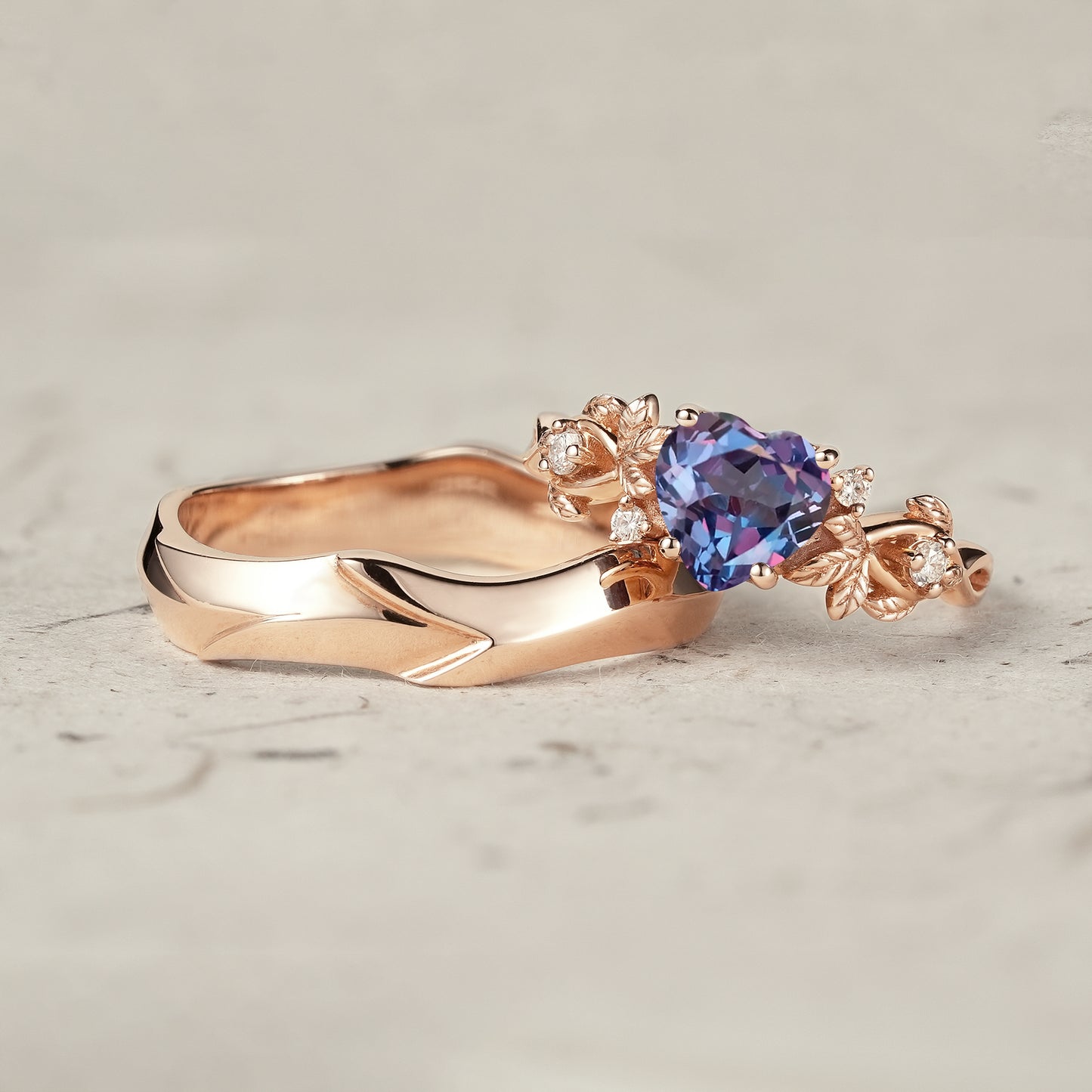 Heart-shaped alexandrite ring with delicate gold leaves and a sleek matching band.