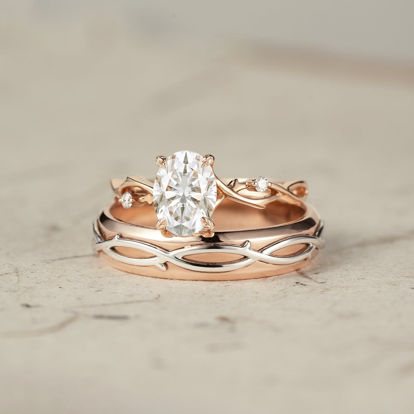 Oval-cut moissanite vine couple's ring set in rose and white gold.