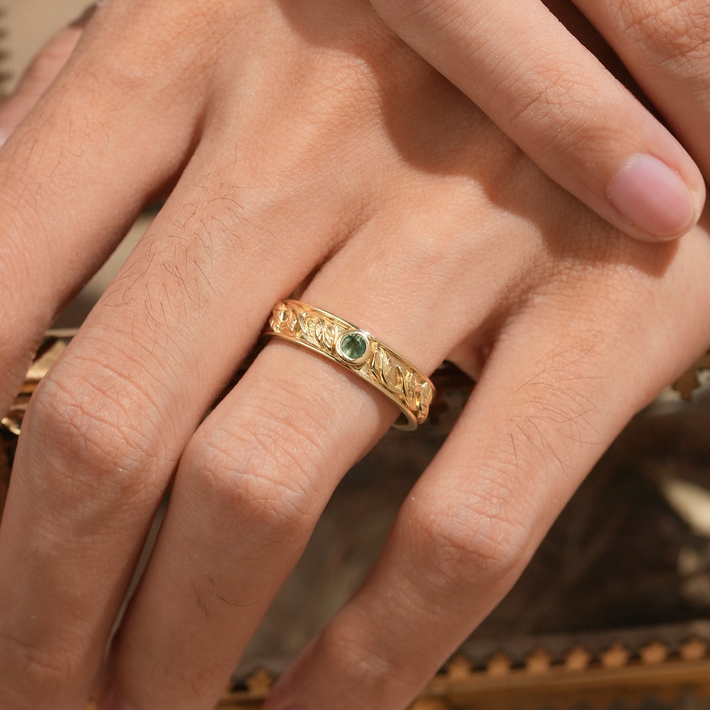 Nature-inspired men's yellow gold moss agate leaf band ring on hand.