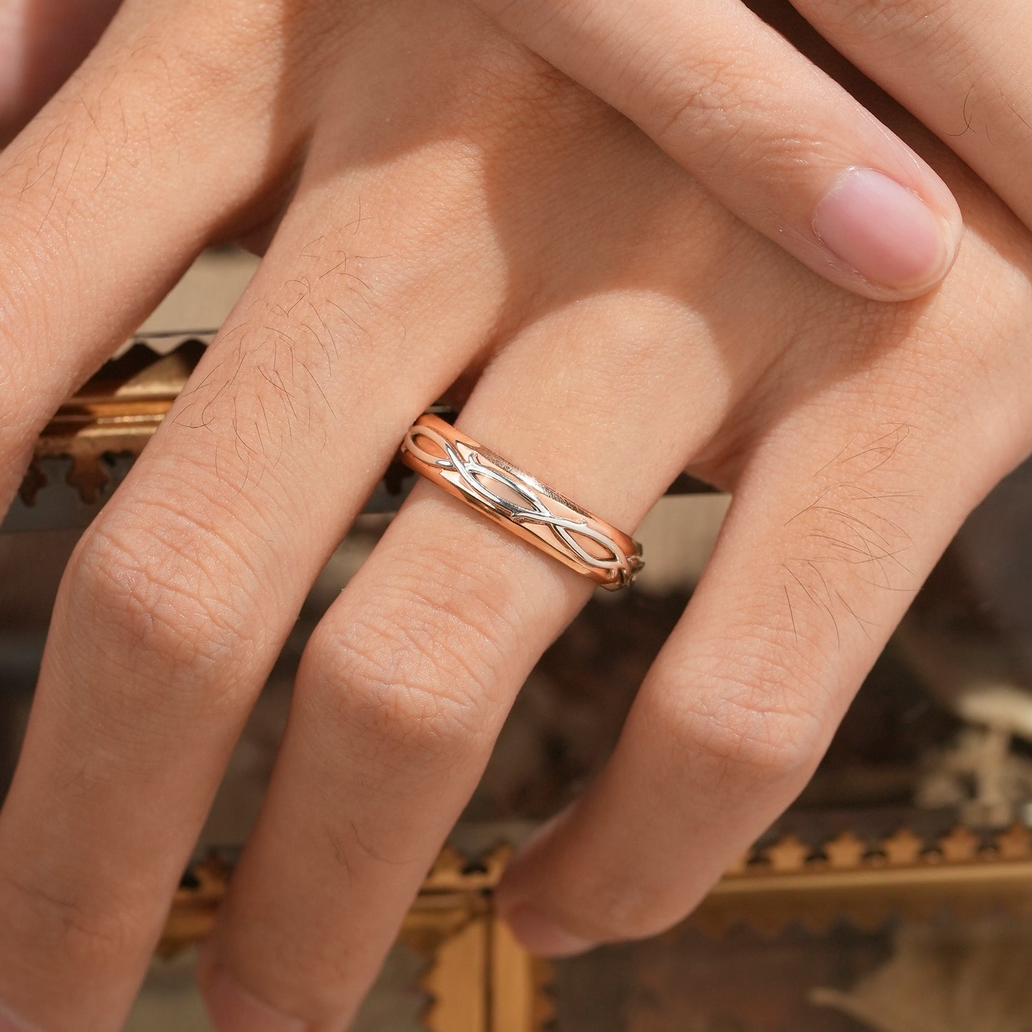 Two-tone men's ring showcasing rose gold and silver vine design on hand