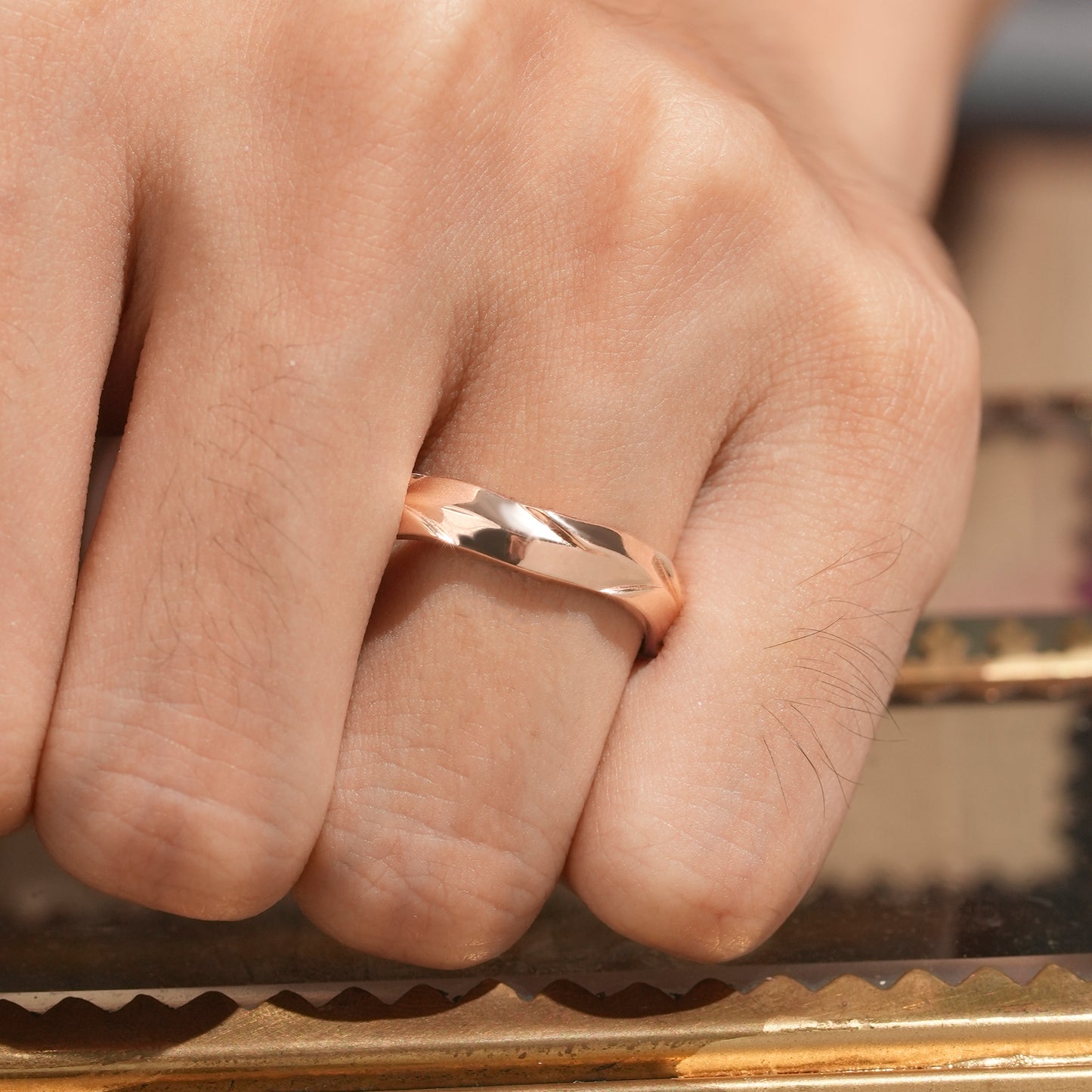 Close-up of modern men's ring in polished rose gold featuring a sculpted angular design.