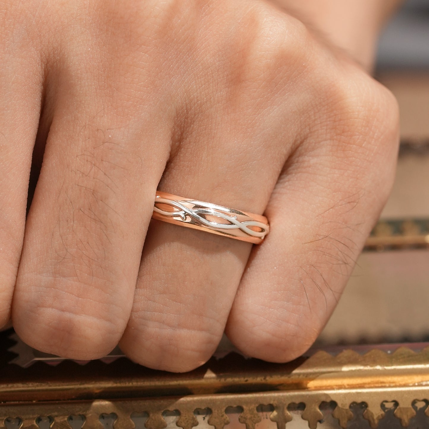 Men's two-tone ring with intertwined rose gold and silver vine design on hand