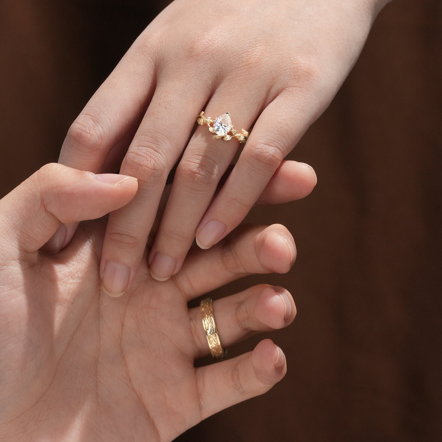 Close-up of vine-inspired moissanite engagement and wedding rings in yellow gold.