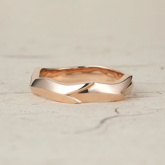 Sculpted modern men's ring in polished rose gold with unique wave-inspired design.