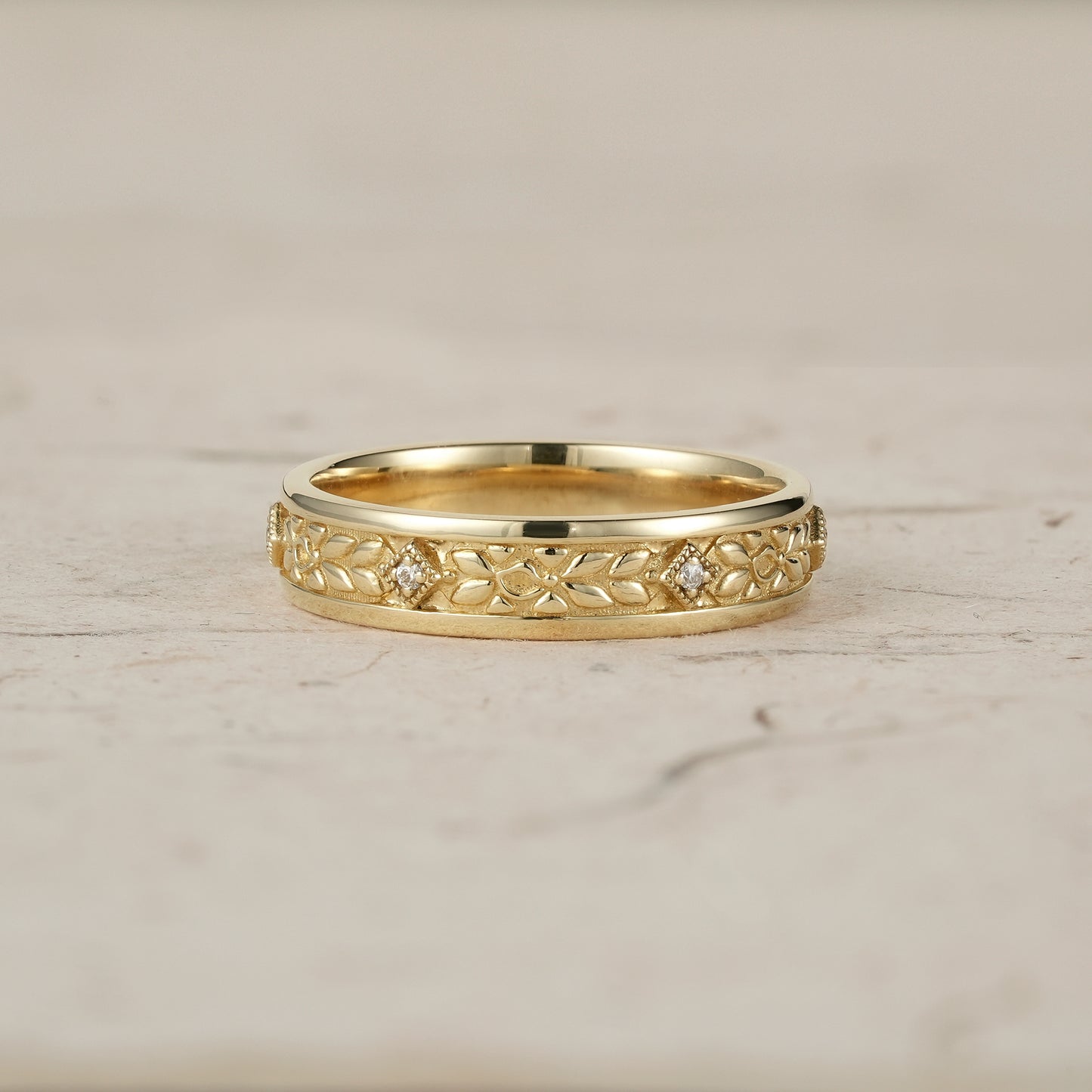 Men's gold ring featuring intricate leaf engravings and moissanite accents.