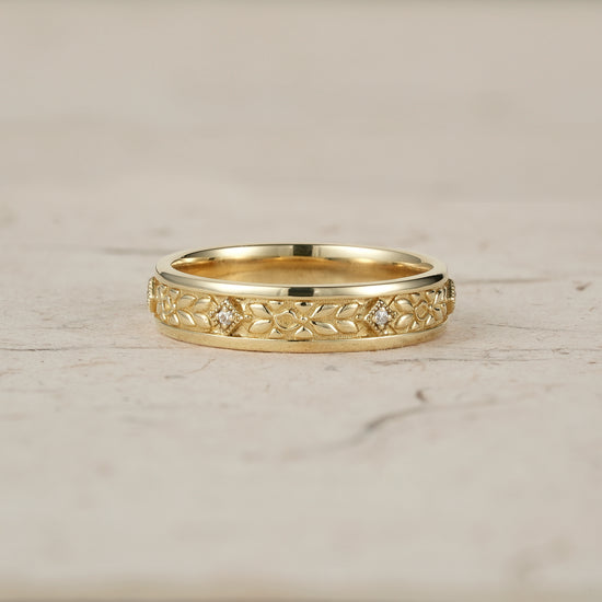 Men's gold ring featuring intricate leaf engravings and moissanite accents.