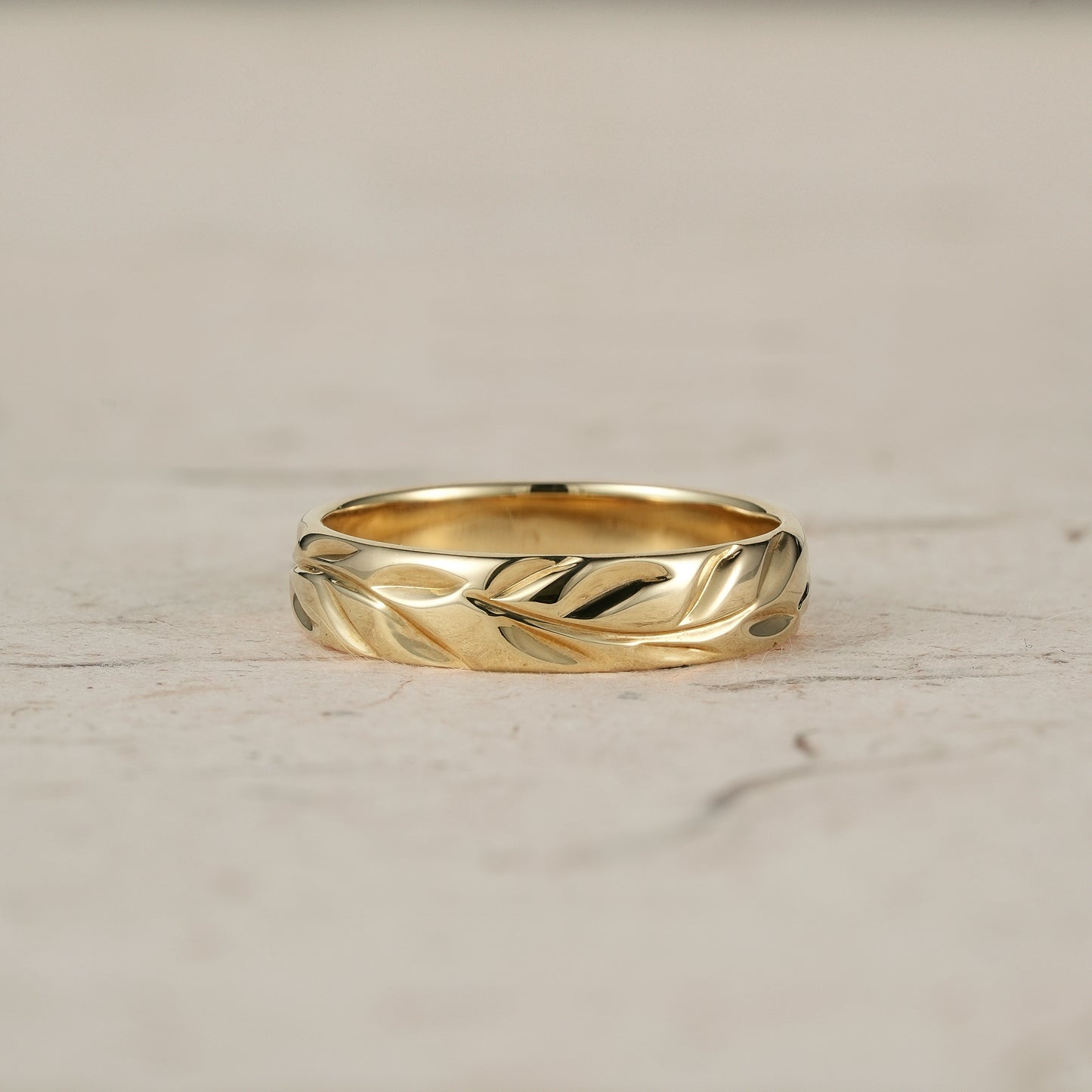 Polished yellow gold men's ring with intricate leaf engraving, showcasing vintage style.