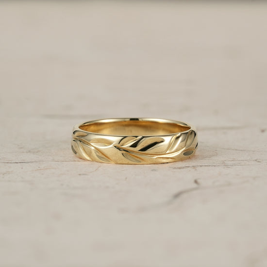 Polished yellow gold men's ring with intricate leaf engraving, showcasing vintage style.