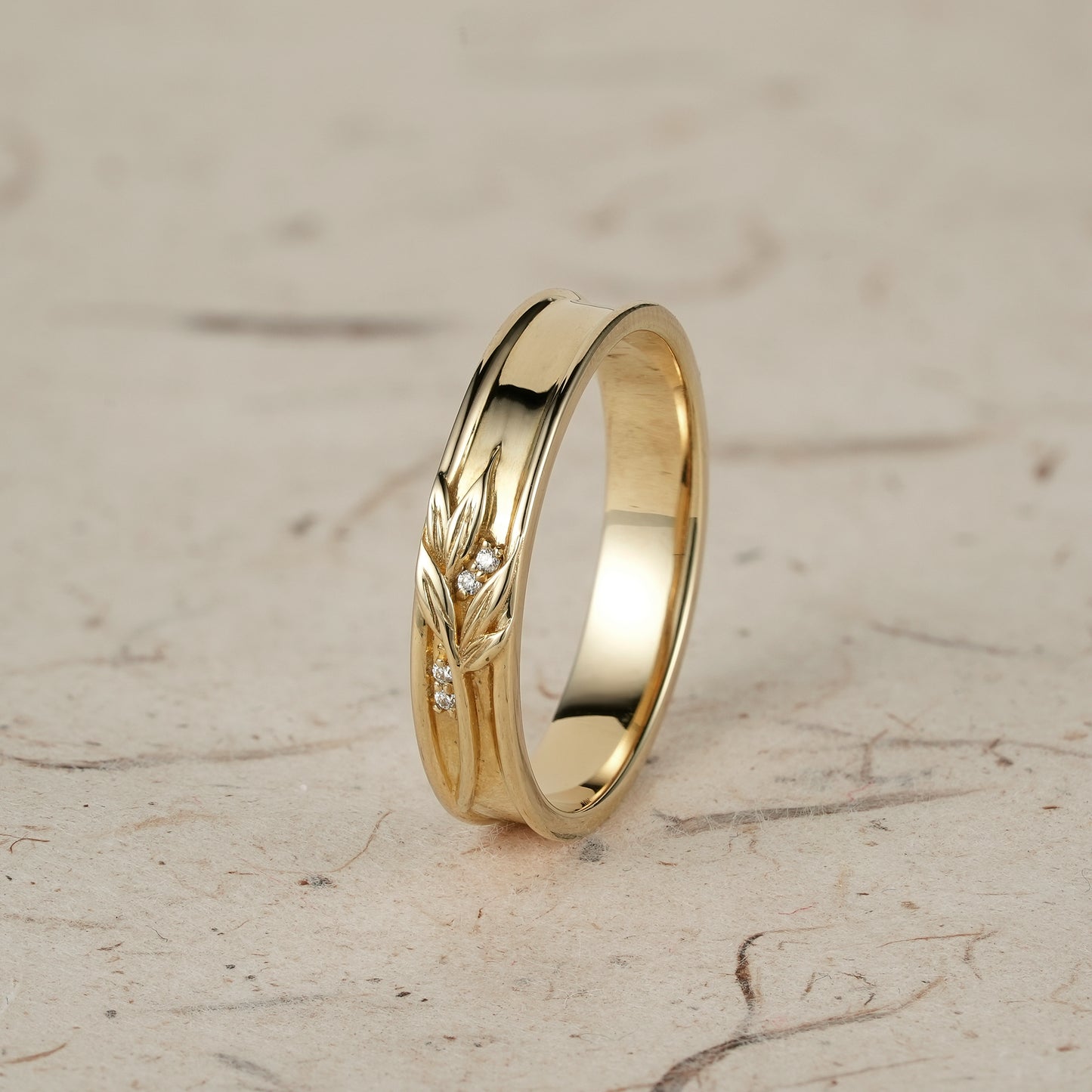 Men's gold band with intricate leaf motifs and subtle diamond accents