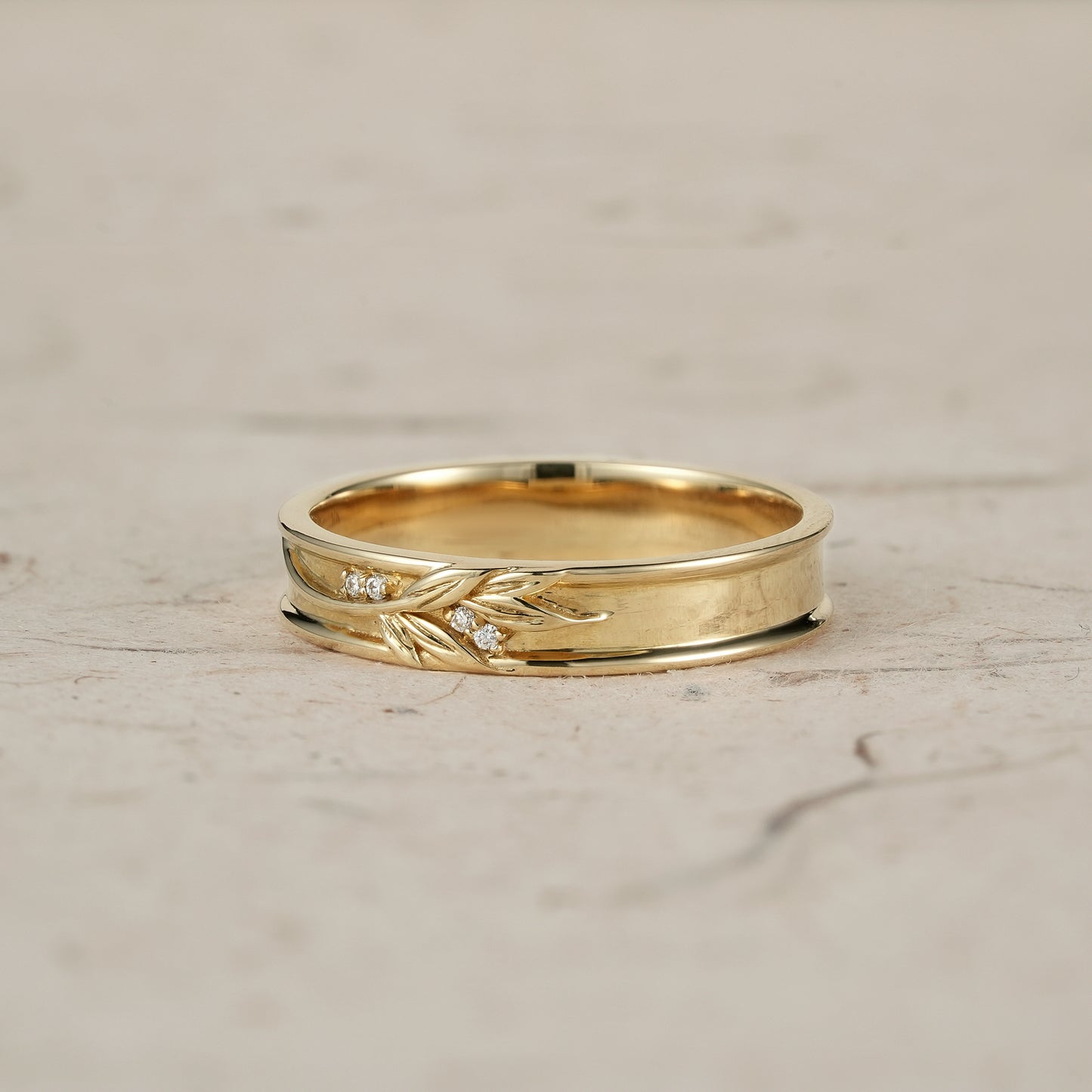 Gold men's ring with elegant leaf engravings and diamond accents.