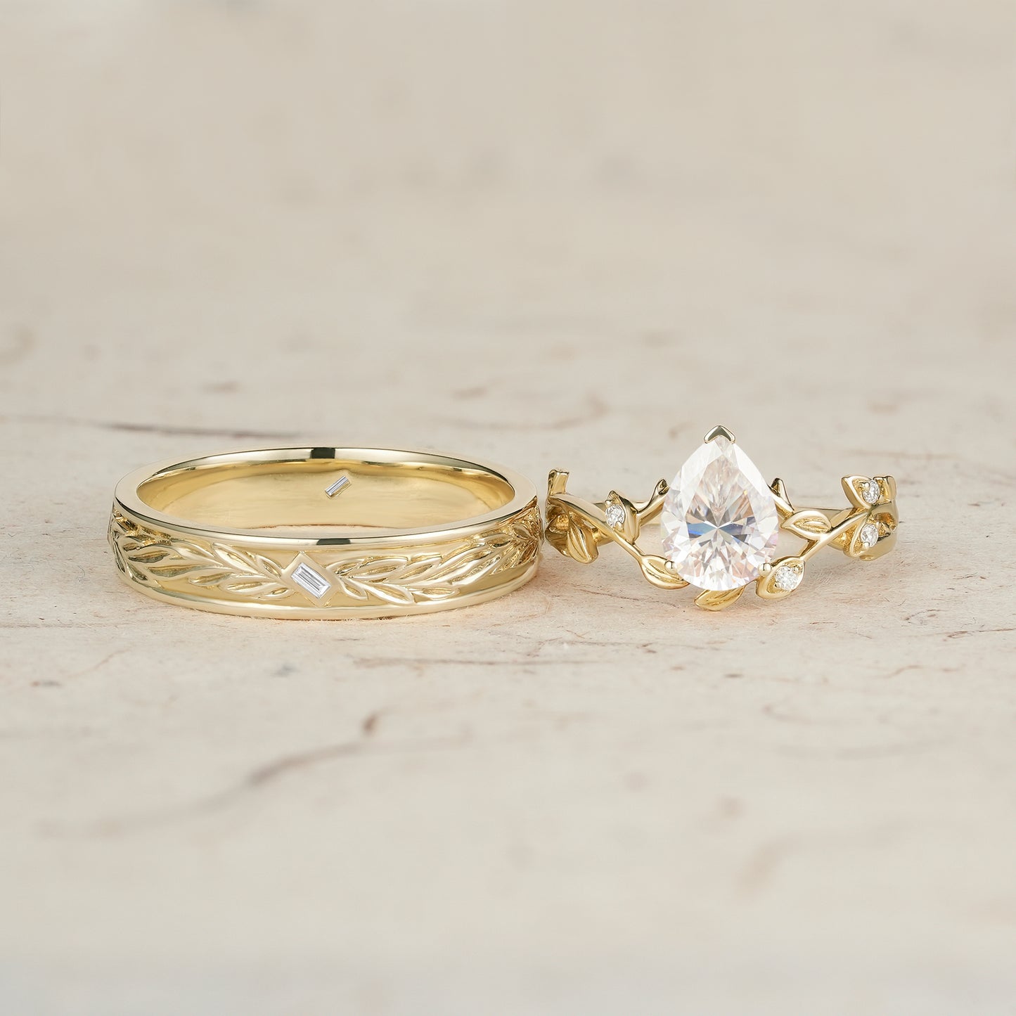 Yellow gold vine-inspired moissanite engagement ring with pear-cut stone and textured band.