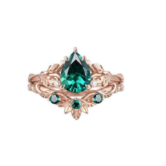 Nature-inspired engagement ring with pear-cut emerald and floral accents in rose gold.