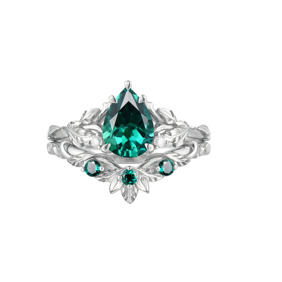 Floral engagement ring with pear-cut lab emerald and green stone accents in silver setting