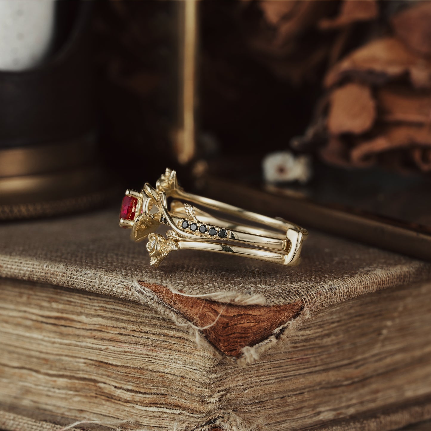 Rose Blossom ruby ring with floral design and black onyx on antique book background