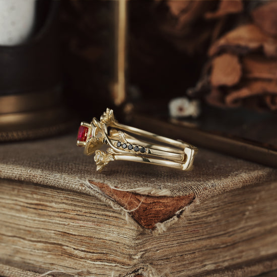 Rose Blossom ruby ring with floral design and black onyx on antique book background