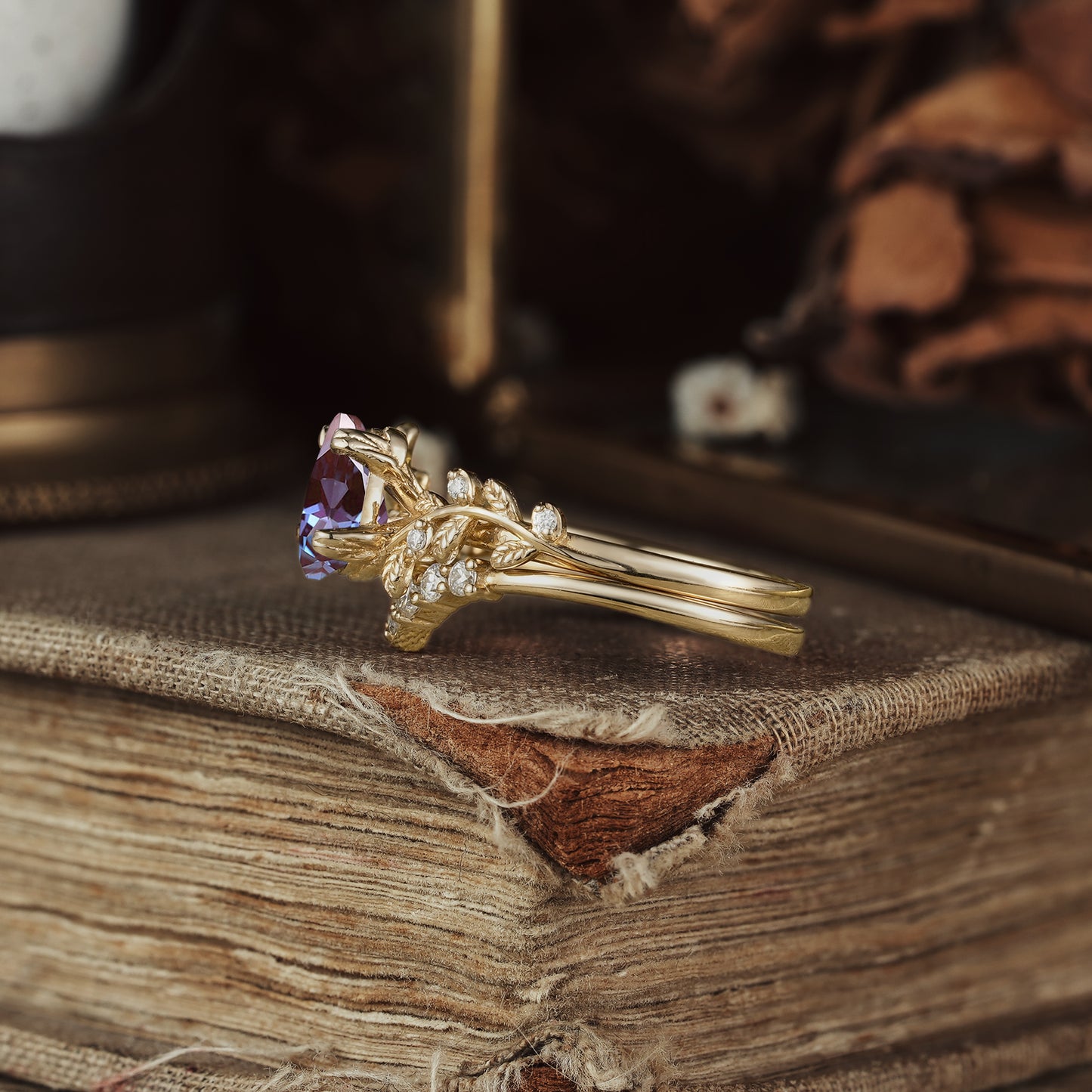 Gold engagement ring featuring pear-cut alexandrite and botanical leaf design accents