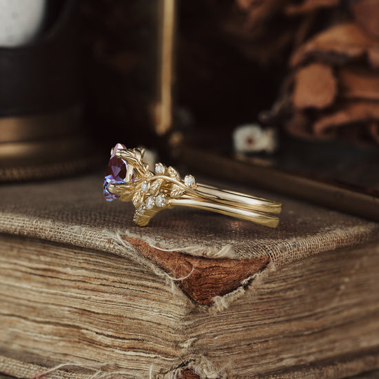 Gold engagement ring featuring pear-cut alexandrite and botanical leaf design accents