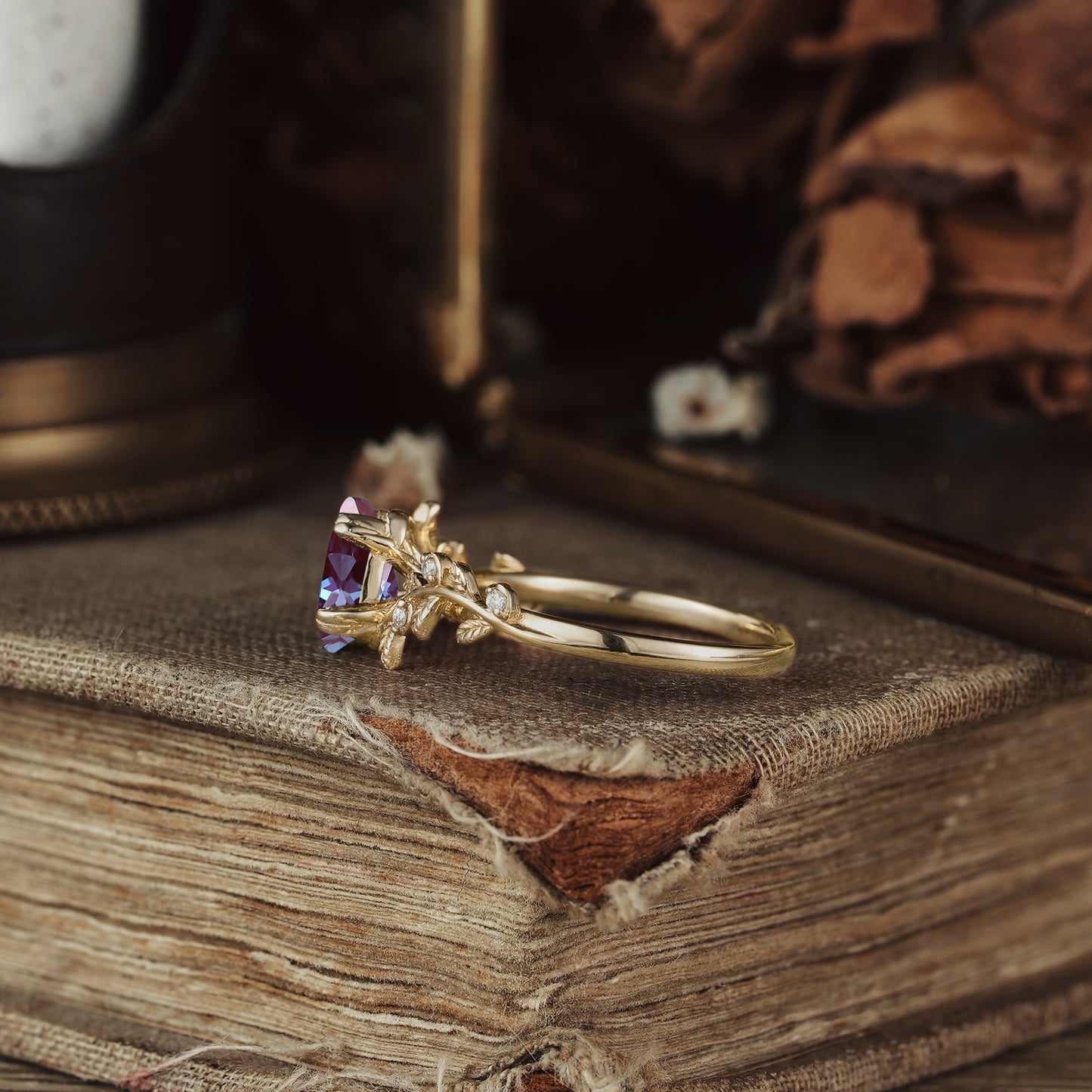 Pear-shaped alexandrite ring with leaf design on a vintage book