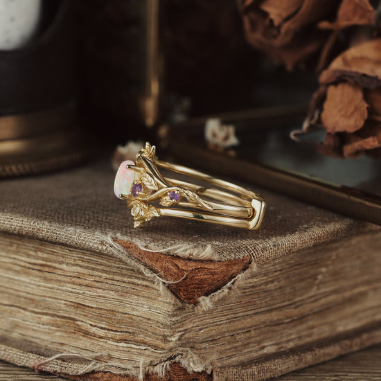 Gilded opal ring with floral gold details and amethyst on vintage book setting.