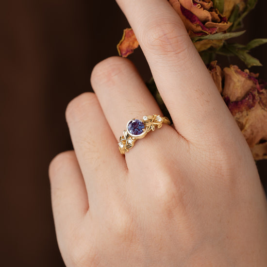 Gold floral ring with round alexandrite and moissanite accents on a hand