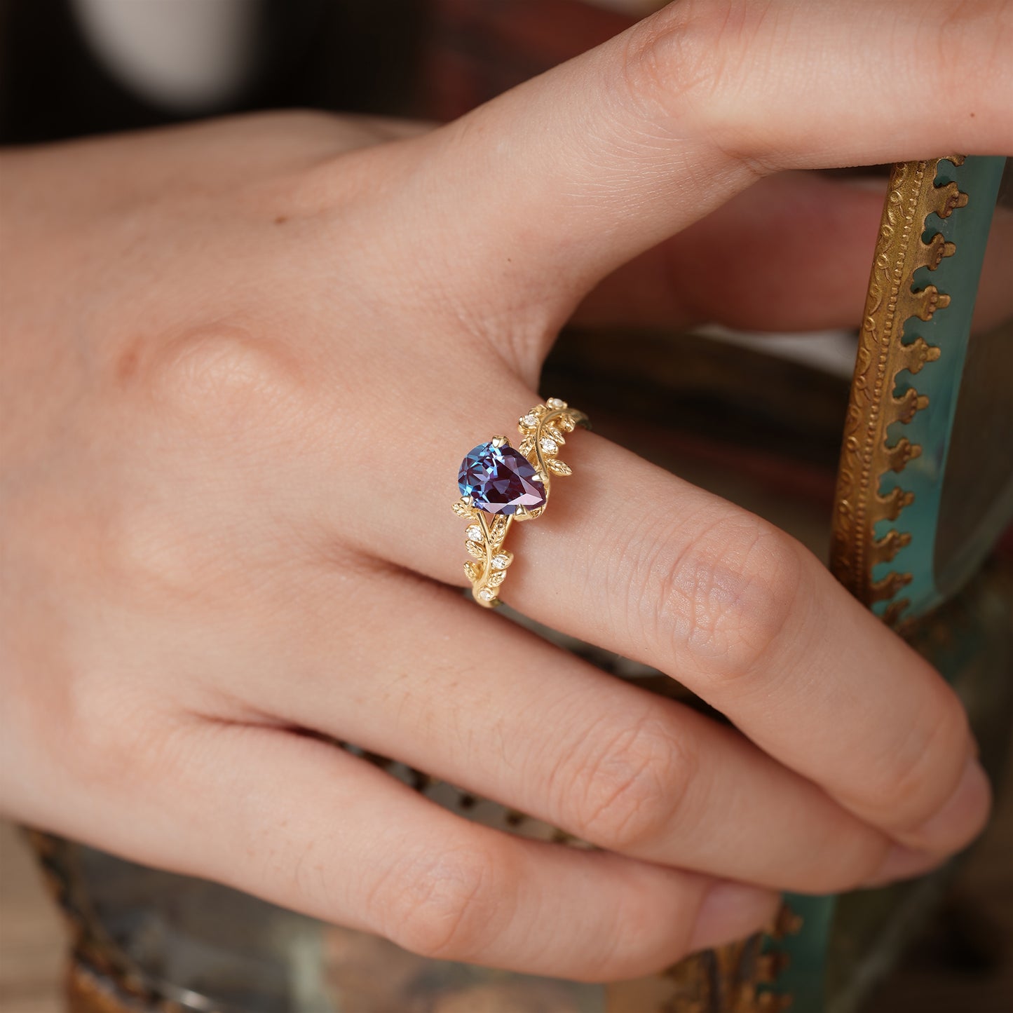 Hand adorned with a unique leaf-inspired alexandrite ring in gold.