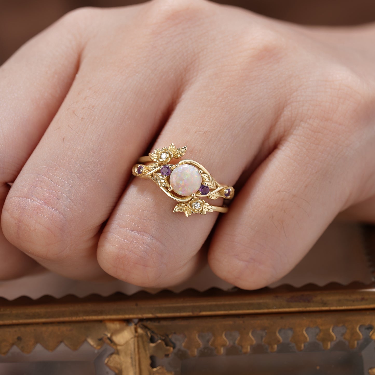 Nature-inspired opal ring set with amethyst and gold leaf details, highlighting floral elements.