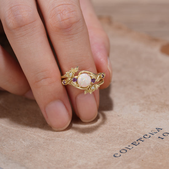 Nature-inspired opal ring set with amethyst on a textured surface, accentuating floral designs.