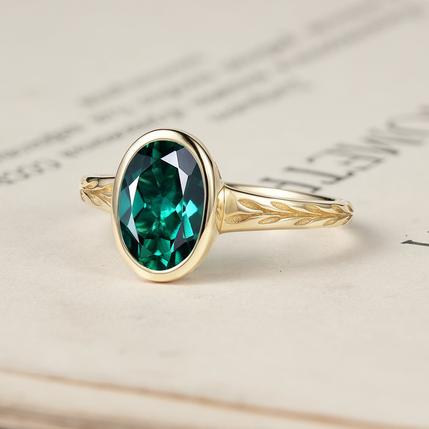 Gold leaf design ring featuring a stunning oval emerald on a textured band.