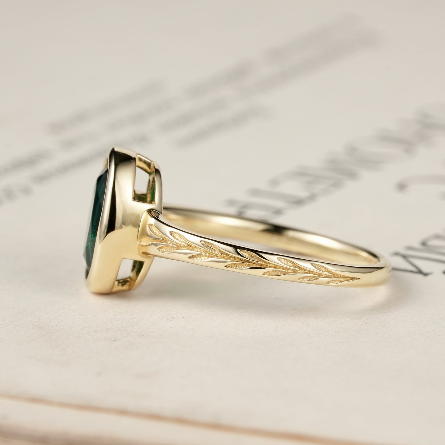 Gold ring showcasing an oval emerald with elegant leaf motifs on the band.