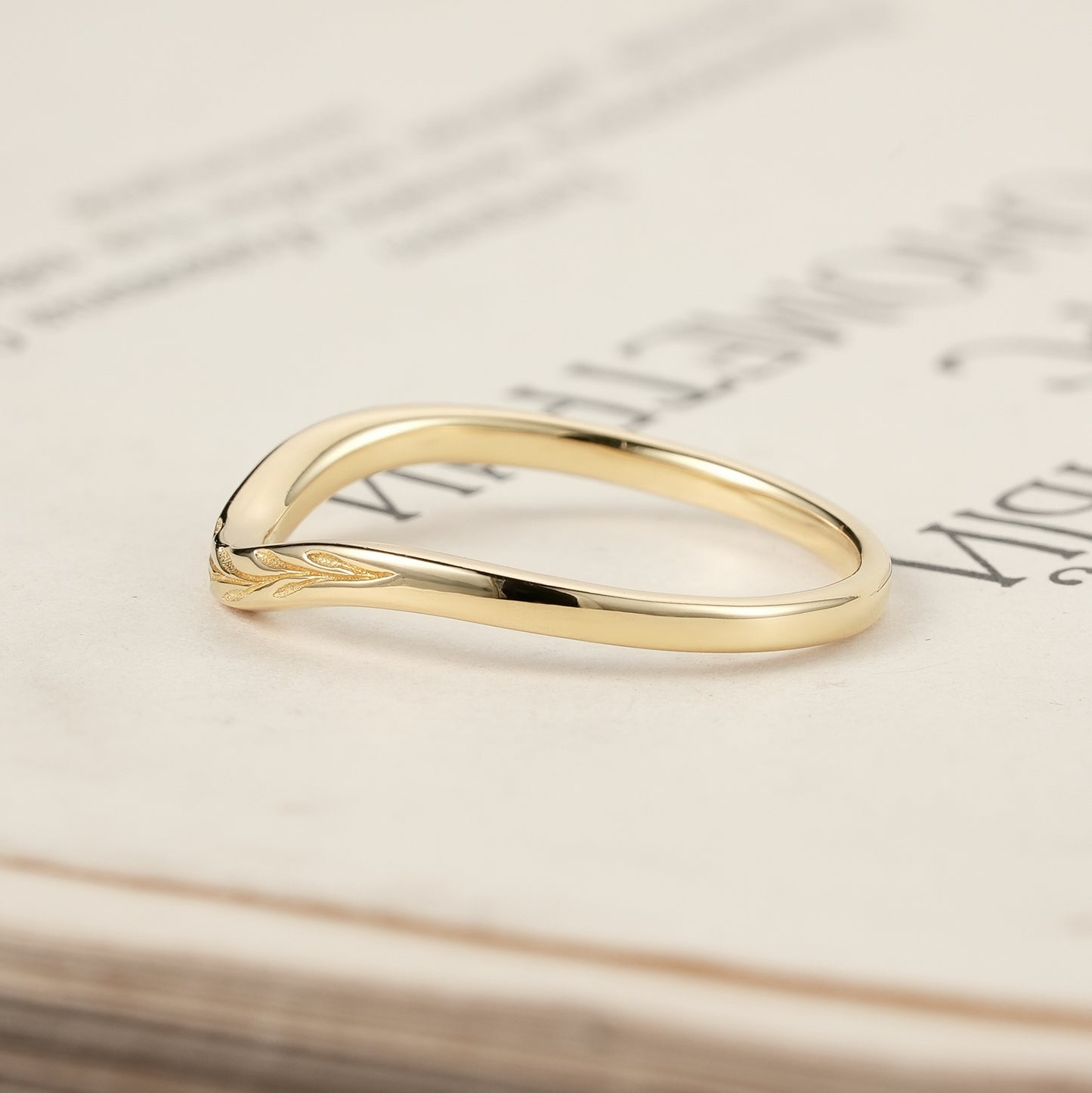 Elegant gold ring with embossed leaf design resting on a book page