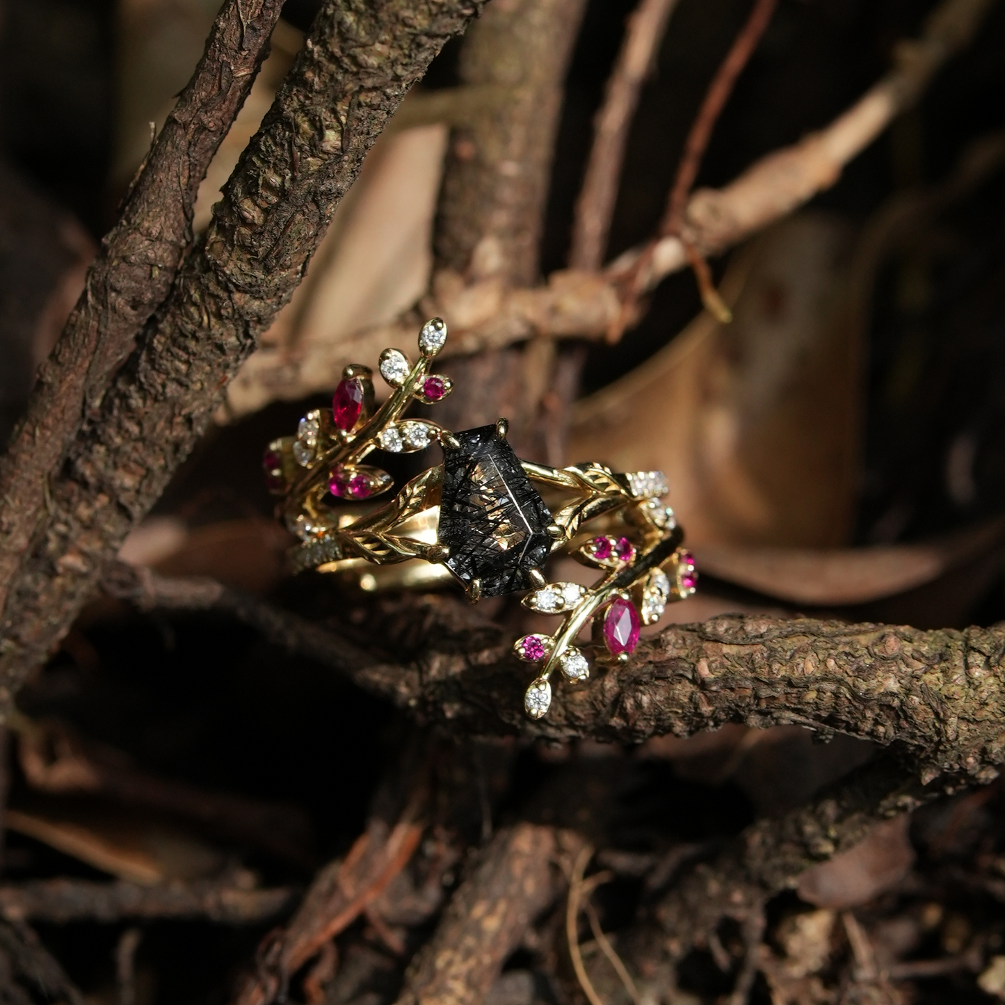 Elegant black rutilated quartz ring set with rubies and moissanite on a twined golden band.