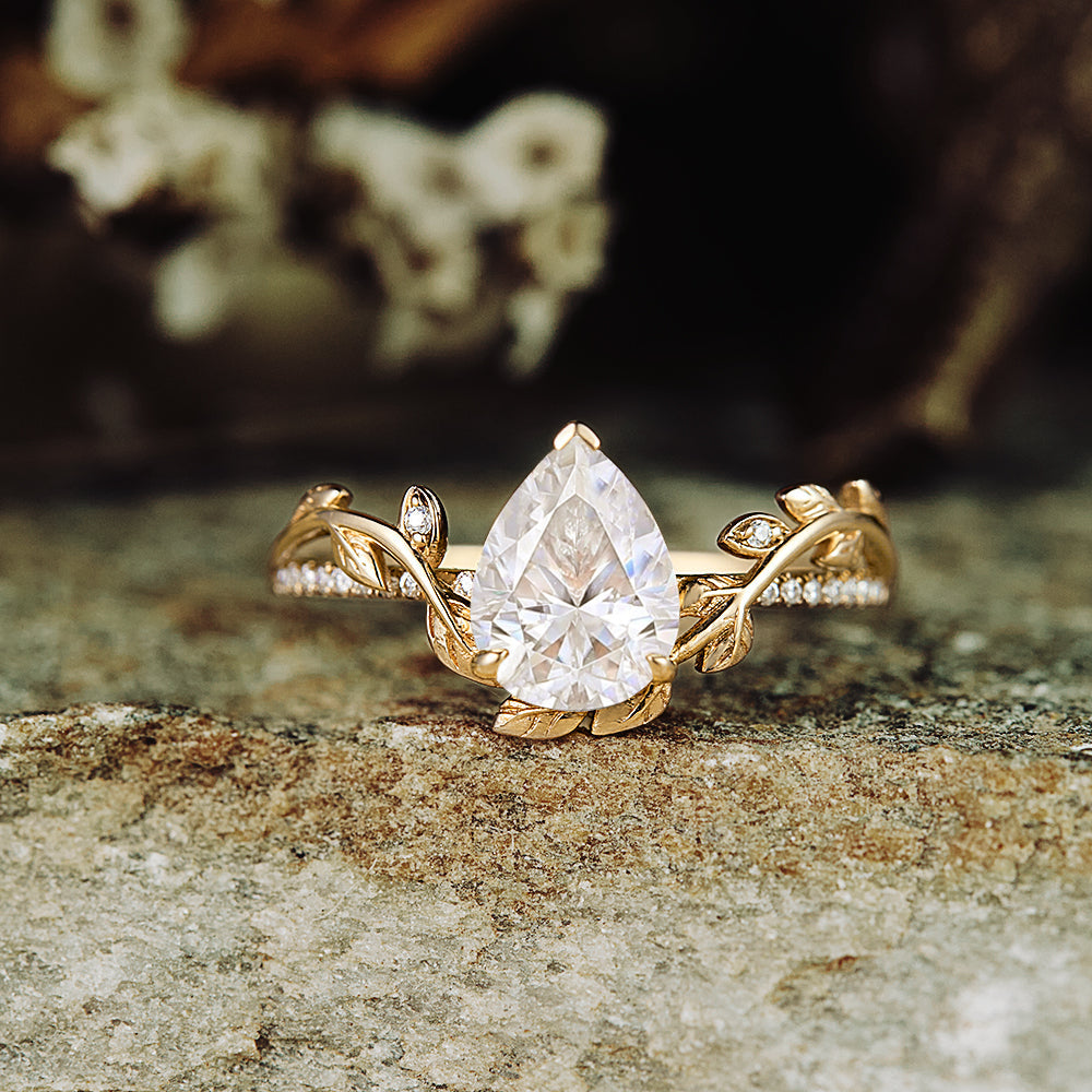 Nature-inspired pear moissanite engagement ring with leaf design in gold.