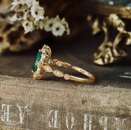 Vintage gold emerald engagement ring with diamond accents set against a textured backdrop.