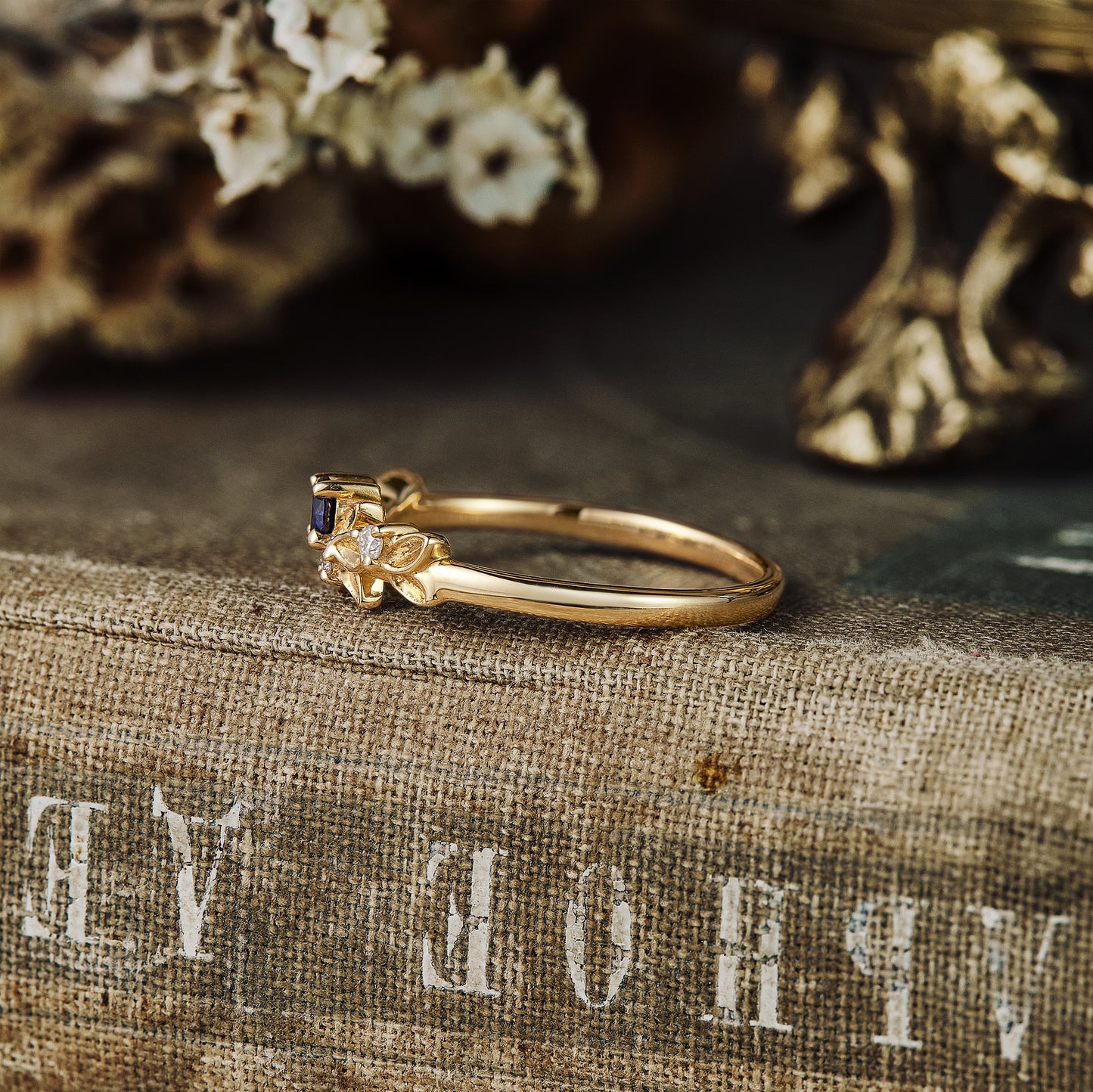 Gold leaf-themed wedding band with sapphire and moissanite on a textured background