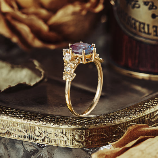 V-shaped gold engagement ring with lab alexandrite and moissanite accents on leaf band.