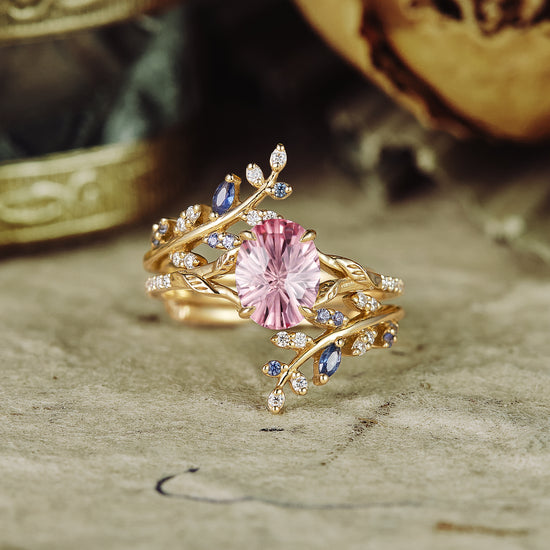 Padparadscha engagement ring with moissanite and sapphire accents, gold vine design.