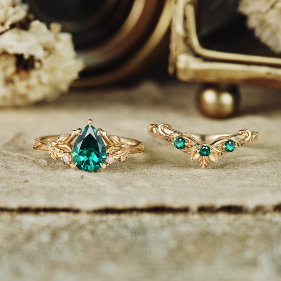 Emerald engagement ring set with floral accents and moissanite details in gold.