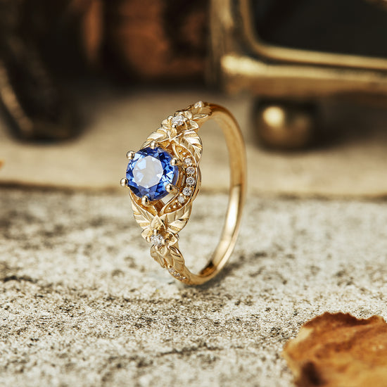 Gold engagement ring with round lab-grown sapphire and leaf design accents