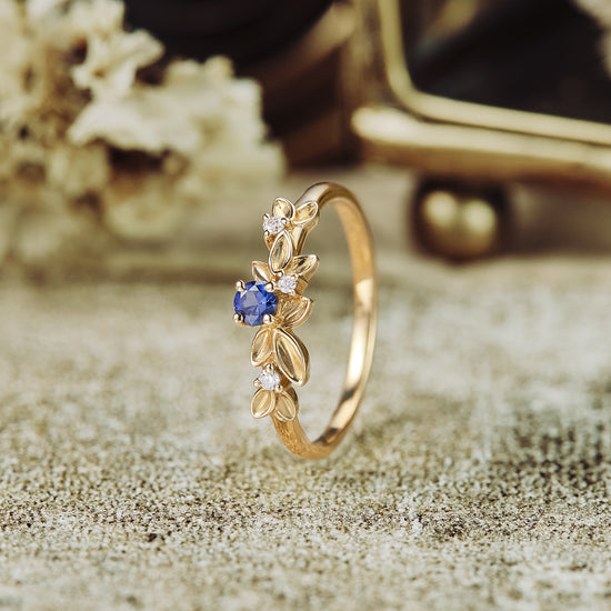 Gold wedding band with sapphire and moissanite, featuring delicate leaf designs