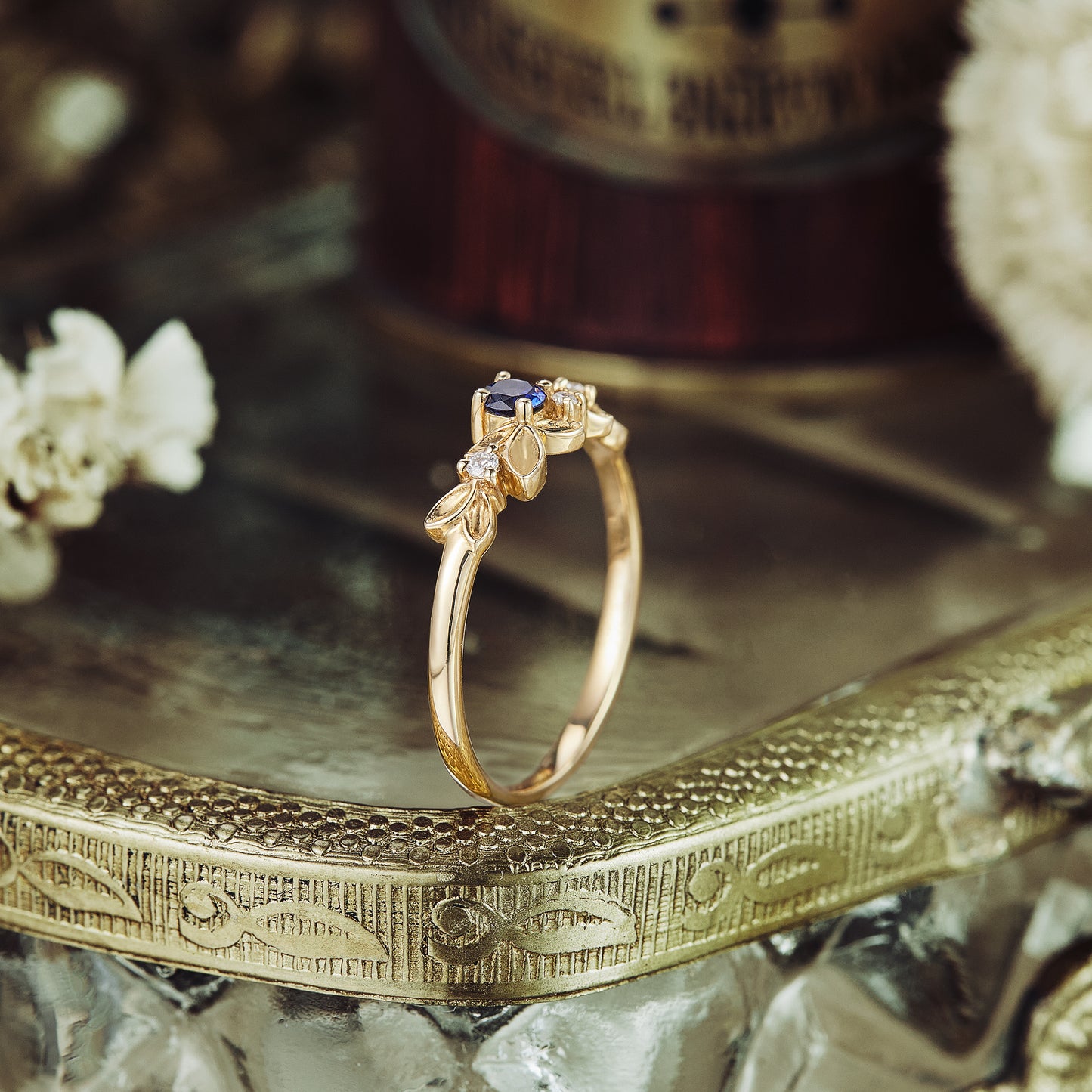 Sapphire and moissanite leaf wedding band in gold on decorative tray