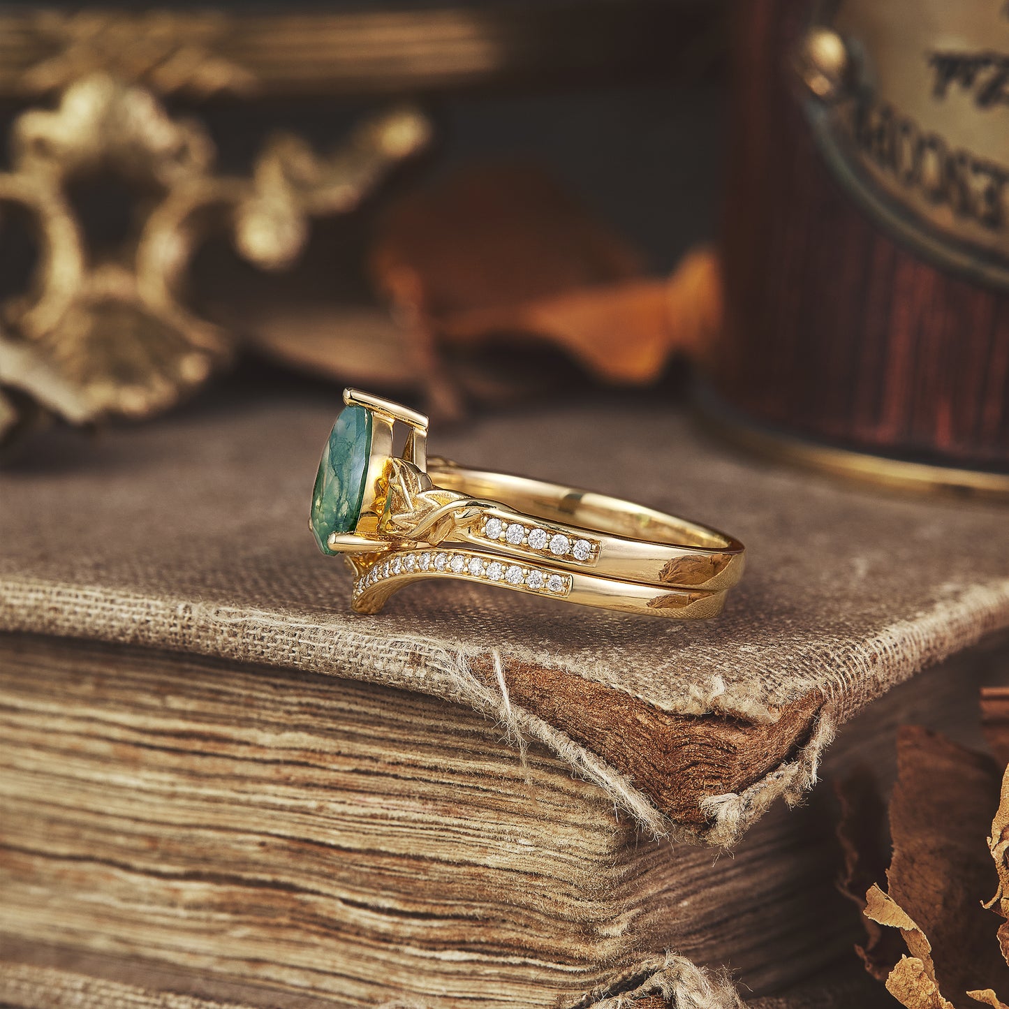 Asymmetric moss agate engagement ring with moissanite, set on a vintage book.