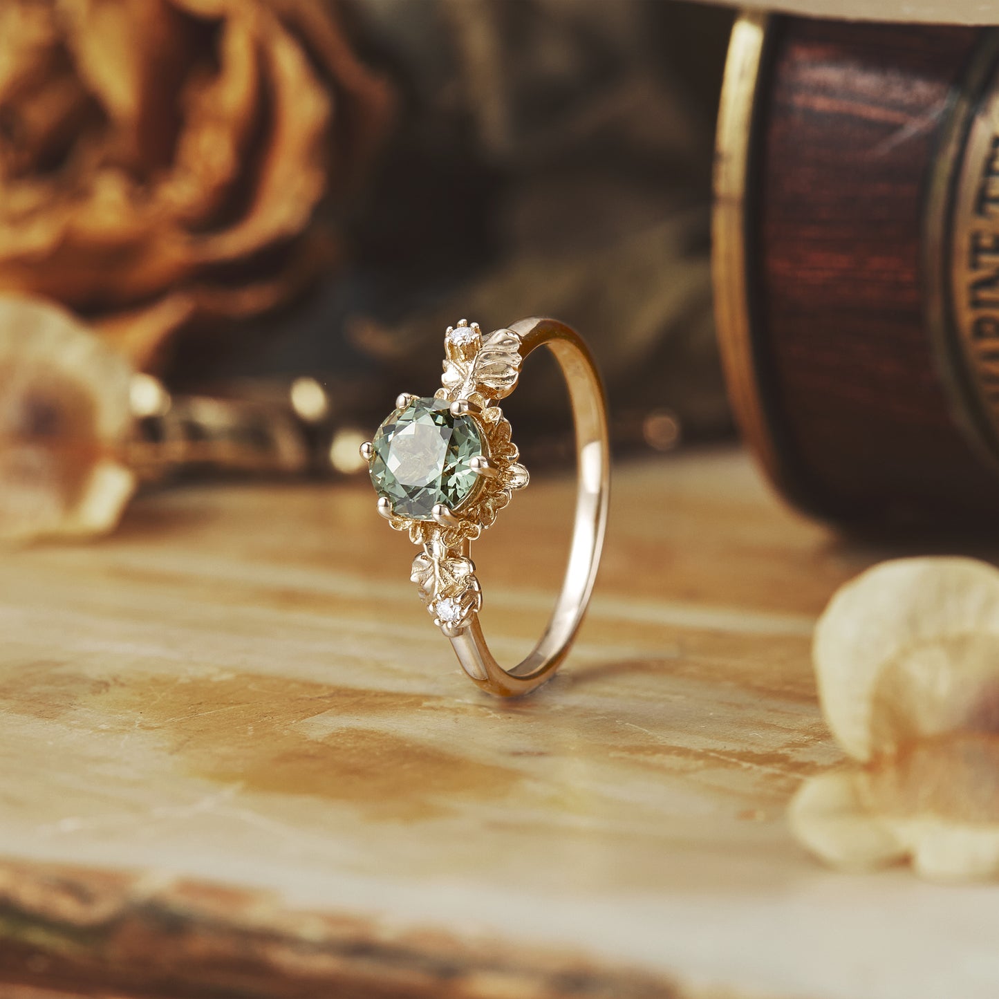 Beekeeper Garden Ring with round green sapphire and leaf designs on wooden surface.