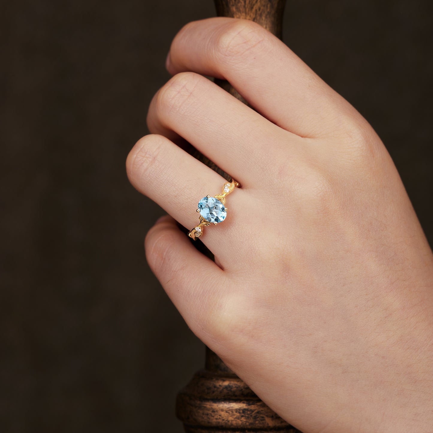 Hand showcasing vintage aquamarine engagement ring in gold setting.