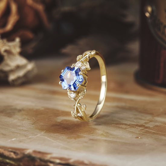 Gold hexagon sapphire ring with vine and leaf details, featuring moissanite accents.