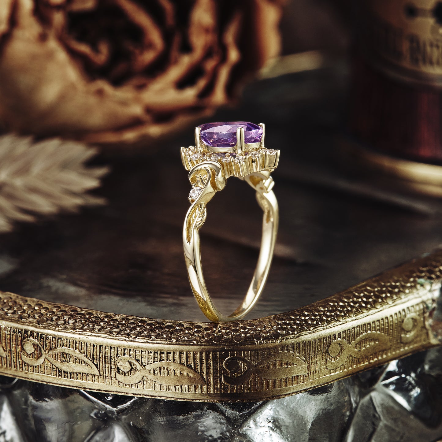 Gold engagement ring with twisted band and pear-shaped purple sapphire stone.