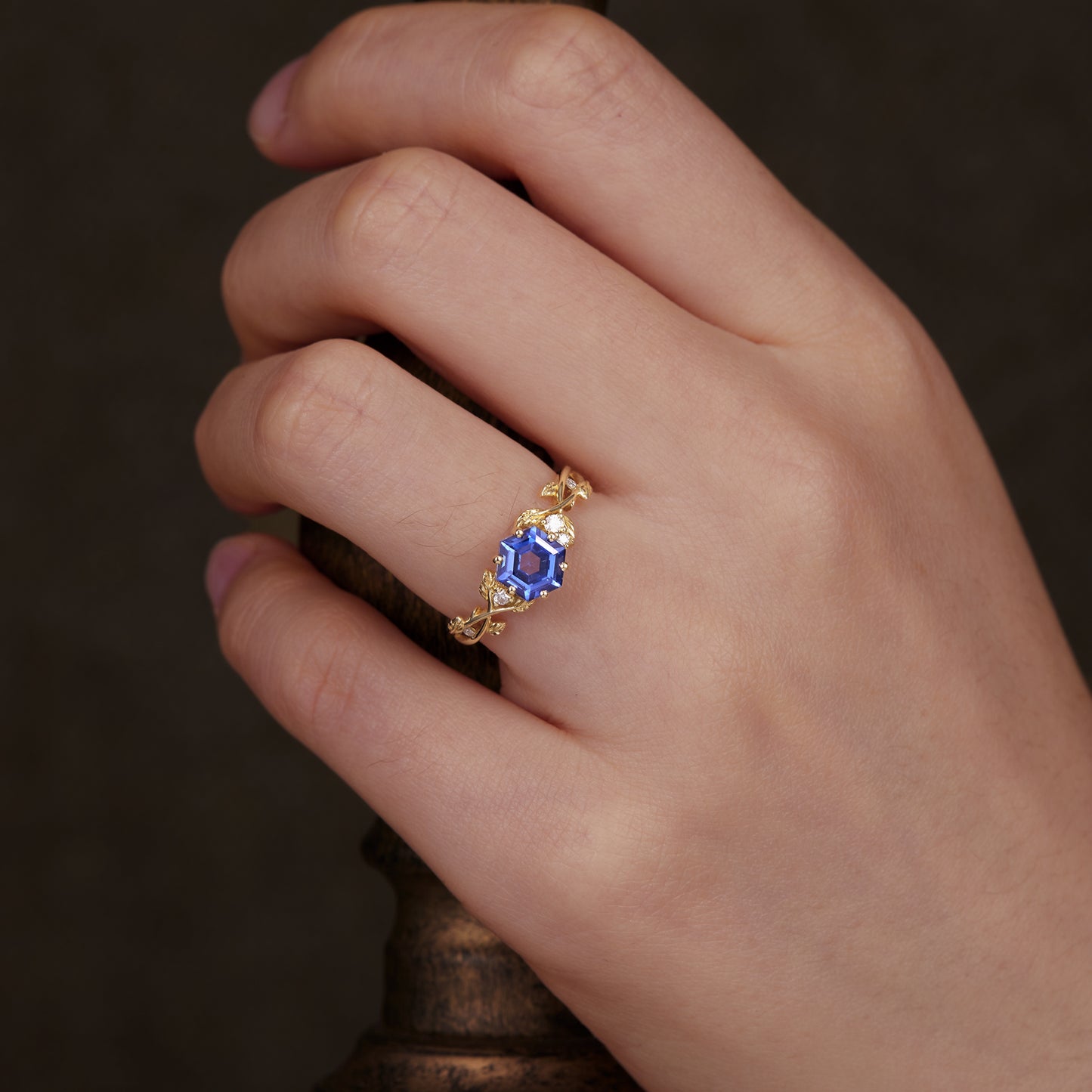 Hexagon sapphire vine ring on hand, showcasing gold band and moissanite accents.