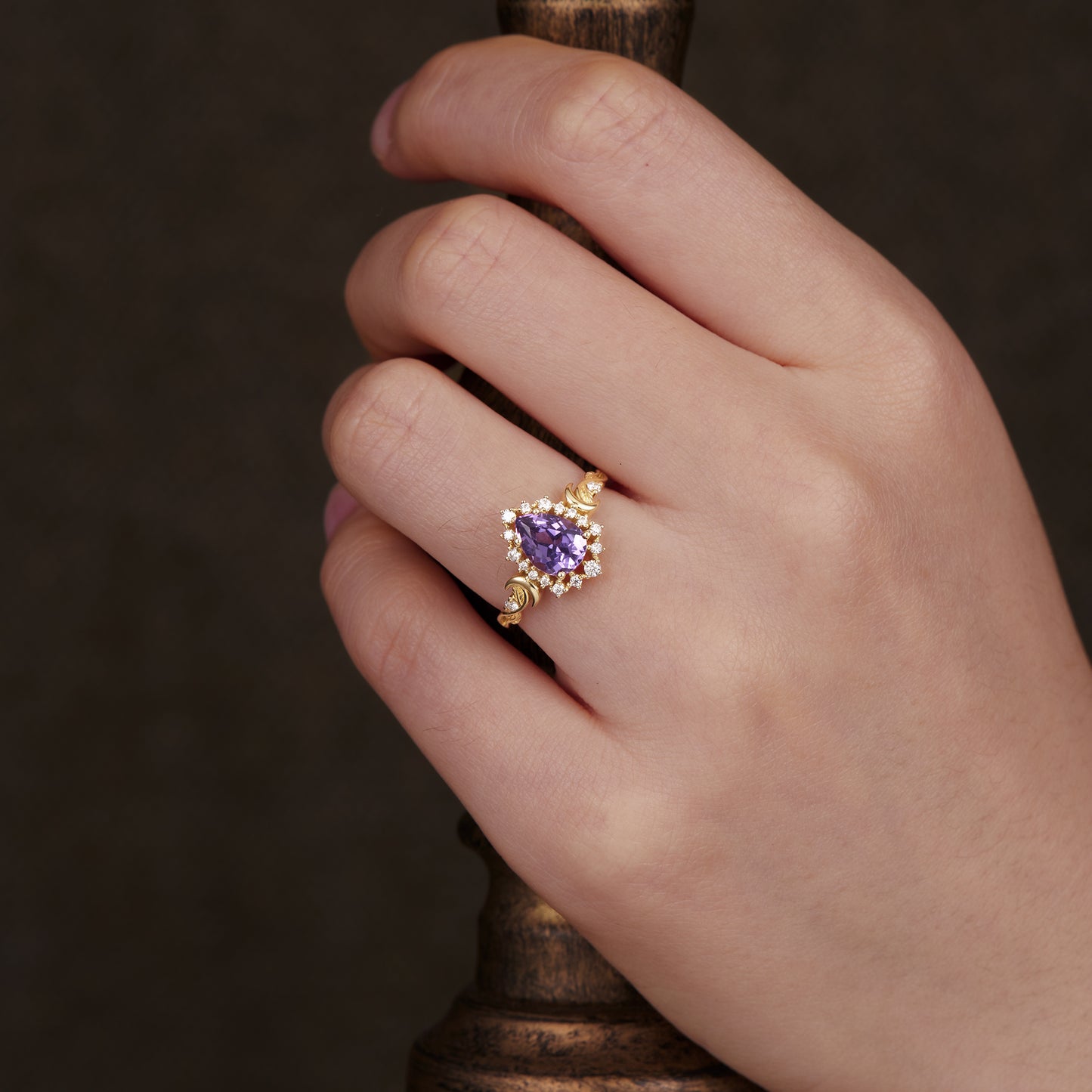 Nature-inspired purple sapphire ring on hand with leaf details and moissanite accents.