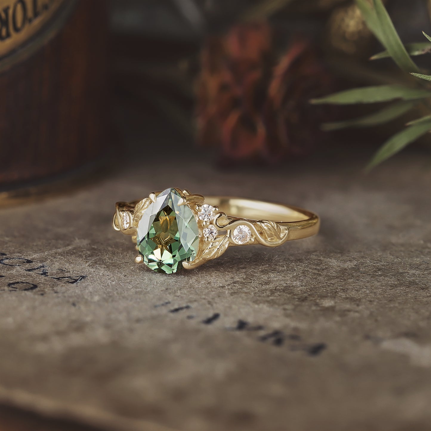 Gold leaf-inspired ring with pear-shaped green sapphire and sparkling diamond accents