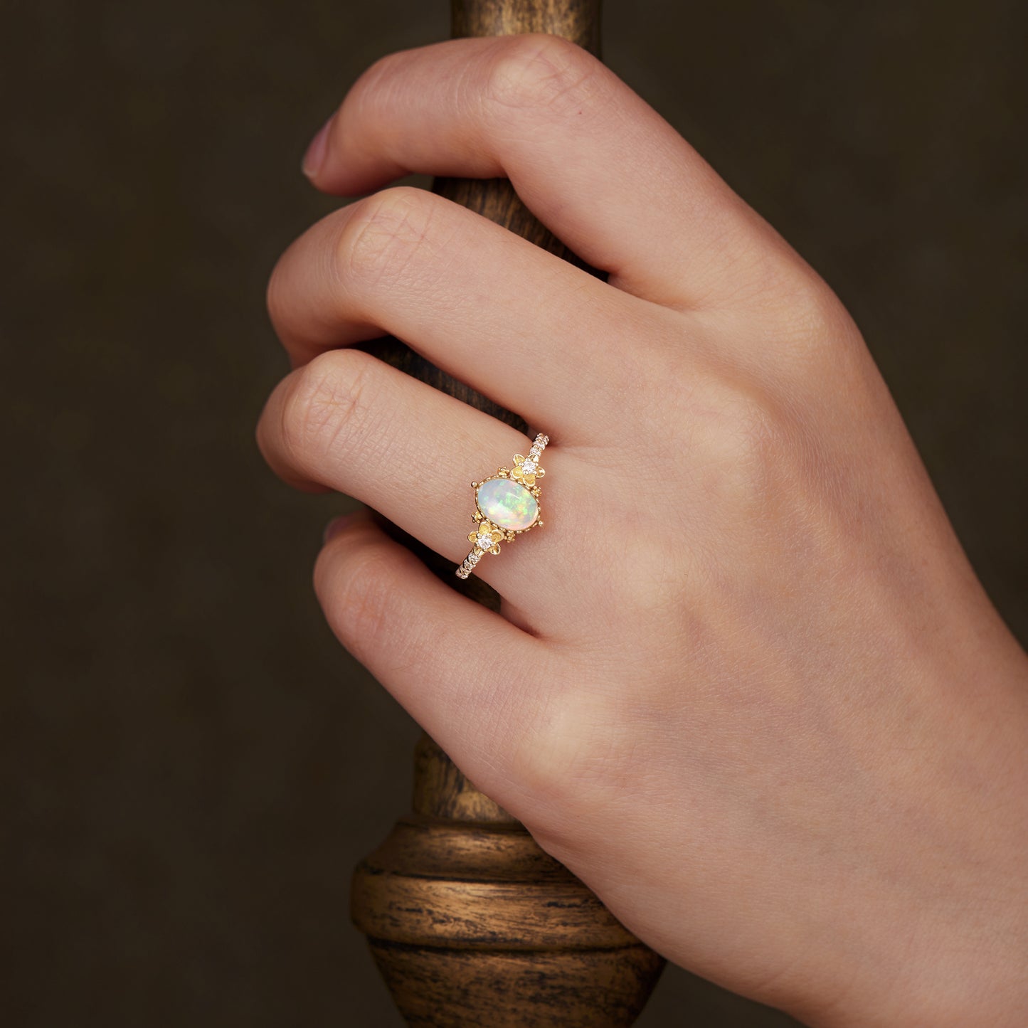 Engagement ring with opal and intricate floral details on gold band, showcasing elegance.